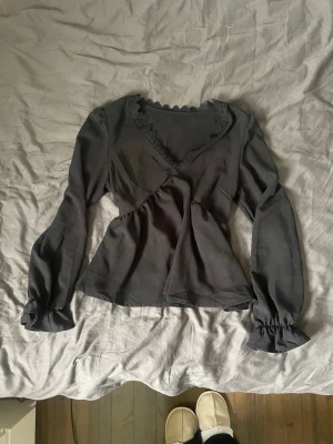 Svart blus - Säljer en svart blus med v-ringning och volangkant längs halsen. Endast använd 1 gång💓 Blusen har ärmar med resår. Perfekt till både jeans och kjol.
