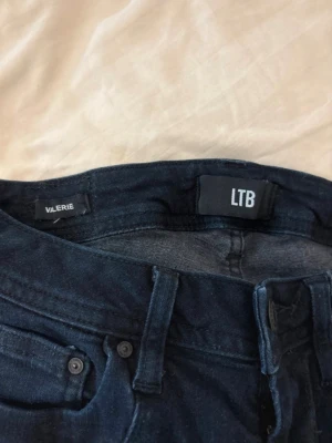 Mörkblå skinny jeans från LTB - Snygga mörkblå skinny jeans från LTB, modell Valerie. Klassisk femficksdesign med knappgylf och bälteshällor. Jeansen har en smal passform och är tillverkade i stretchigt denimtyg för extra komfort.