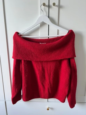 Röd off shoulder stickad tröja - Trendig röd stickad tröja med bred off shoulder-krage och långa ärmar. Mjuk och skön, perfekt för kyliga dagar. Passar dig som vill ha en enkel men snygg look. Materialet känns som en ullblandning.
