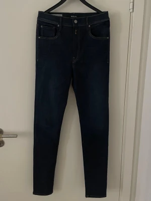 Replay jeans  - Tjena! Säljer ett par snygga mörkblå slim jeans från Replay med klassisk femficksdesign och kontrastsömmar. Jeansen har hög midja och smal passform hela vägen ner. Perfekta till en avslappnad eller trendig look. Modell leyla som troligen är dam modell men killar kan såklart ha dom också. Ingen skillnad!! Skicket är 10/10 och storlek 31/32