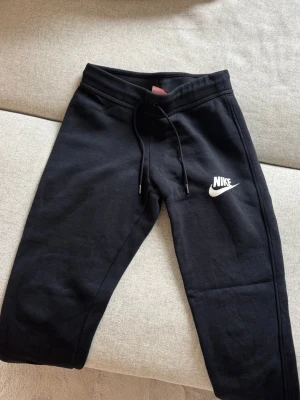 Svarta mjukisbyxor från Nike - Snygga svarta mjukisbyxor från Nike med klassisk vit logga på benet. Använd ett fåtal gånger så är i mycket bra skick.