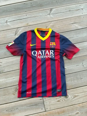 Barcelona matchtröja röd/blå Nike - Säljer en FC Barcelona matchtröja från Nike med klassiska röda och blå vertikala ränder, gul V-ringad krage och klubbmärke på bröstet. Qatar Airways-logga på framsidan och Dri-FIT-material som andas. Perfekt för fotbollsträning eller att bära till vardags. Priset är inte hugget i sten så kom med bud!