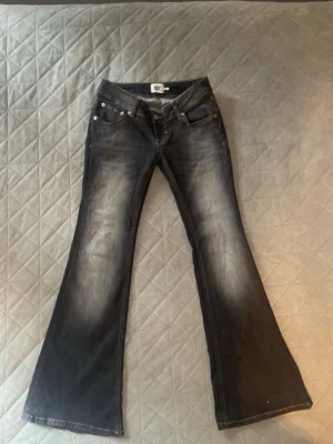 Grå bootcut jeans  - Säljer ett par gråa bootcut jeans med snygga slitningar framtill. Jeansen har låg midja, fem fickor och klassisk knappgylf. Perfekta för dig som gillar en retro och avslappnad stil.