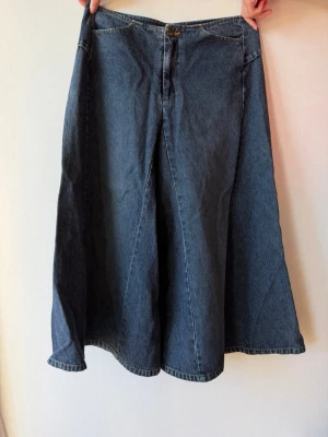 Vida blå jeans från Vila - Säljer ett par vida blå jeans från Vila i klassisk denim. Jeansen har hög midja, utsvängda ben och stängs med knapp och dragkedja framtill. Perfekta för dig som gillar retrostil och vill ha ett statement-plagg i garderoben.
