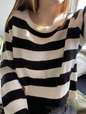 Svartvit randig stickad tröja - Stickad tröja med breda svarta och vita horisontella ränder. Tröjan har rund halsringning, långa ärmar och ribbstickade muddar vid ärmslut och nederkant. Perfekt för en avslappnad och trendig look.