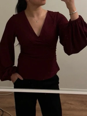 Vinröd blus från NAKD - Vinröd blus med vida ärmar. Har aldrig använts, och glömde lämna tillbaka den i tid. Prislappen är kvar. Den köptes för 399kr men säljer för 250kr