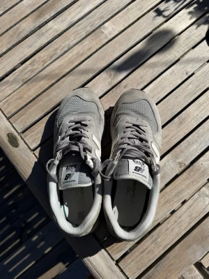 Grå New Balance 574 sneakers - Snygga grå New Balance 574 sneakers med klassisk siluett och stora N-loggor på sidorna. Skorna är i bra kvalité och är i storlek 44! 