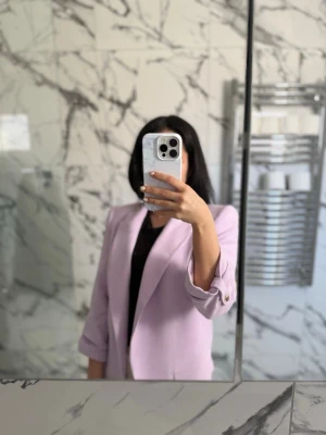 Ljuslila oversized kavaj  - Trendig ljuslila kavaj med oversized passform och axelvaddar. Kavajen har klassisk krage, två knappar vid ärmslut. Använd under ett tillfälle. Inga skador eller defekter. 