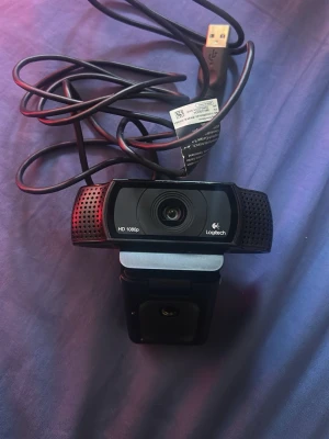 Logitech HD 1080p webbkamera - Säljer en svart Logitech webbkamera med HD 1080p-upplösning. Kameran har en rektangulär form med inbyggd mikrofon på sidorna och ansluts via USB. Perfekt för streaming, videosamtal eller gaming.