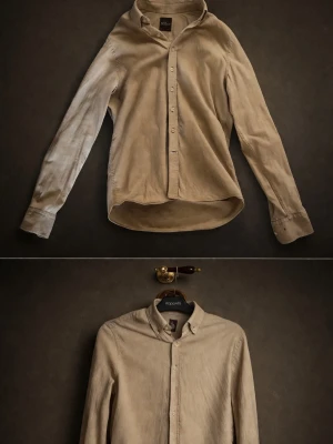 Beige linneskjorta från Oscar Jacobson - Säljer en stilren beige skjorta från Oscar Jacobson i linnematerial. Skjortan har klassisk krage och knappar framtill. Perfekt för dig som gillar en enkel men snygg look. Frågor - hör av er!