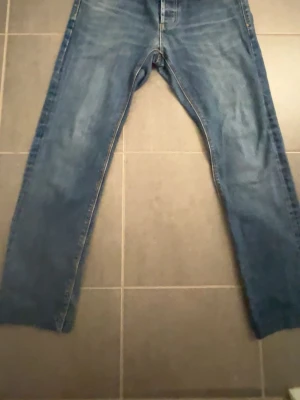 Blå jeans från Superdry - Säljer ett par blå jeans från Superdry med klassisk femficksdesign och snygga detaljer på fickorna. Jeansen har raka ben och är tillverkade i denim med lätt tvättad look. Perfekta för dig som gillar en avslappnad och stilren stil. Storlek 32:32 skulle jag säga och pris kan diskuteras vid snabb affär!