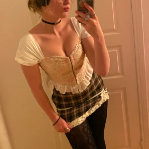 Söt korsett-topp - Säljer en superfin korsett-topp med blommigt mönster och spetsdetaljer. Toppen har en söt volangkant och är i ett tight passform. Man kan också knäppa upp framtill. Perfekt för tex fest eller konsert! 💃