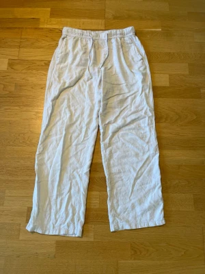 Beige linnebyxor från H&M Relaxed Fit - Säljer ett par beige linnebyxor från H&M med relaxed fit. Byxorna har resår och dragsko i midjan samt raka ben. Perfekta för en chill och avslappnad look, tillverkade i lätt och luftig linneblandning.