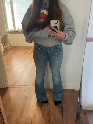 Ljusblå bootcut jeans - Säljer ett par ljusblå bootcut jeans med låg midja och klassisk femficksdesign. Jeansen har en avslappnad passform och är tillverkade i denim med lätt tvättad look. Perfekta för en casual och trendig stil.