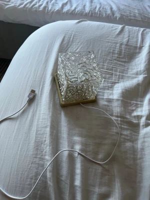 USB-drivna glaslampa med mönster - Säljer en dekorativ glaslampa med USB-kabel. Lampan har ett fyrkantigt, genomskinligt glas med blommigt mönster och en beige botten. Perfekt som mysbelysning till skrivbordet eller nattduksbordet. Kopplas enkelt in via USB.