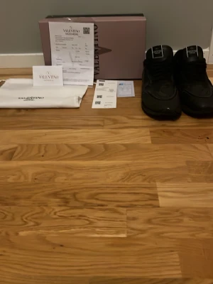 Svarta Valentino Garavani sneakers - Stilrena svarta sneakers från Valentino Garavani med chunky sula och diskreta detaljer. Skorna har en modern siluett och är tillverkade i en mix av läder och textil. Levereras med originalkartong, dustbag och äkthetsbevis. Pris kan diskuteras om ni har frågor skriv!
