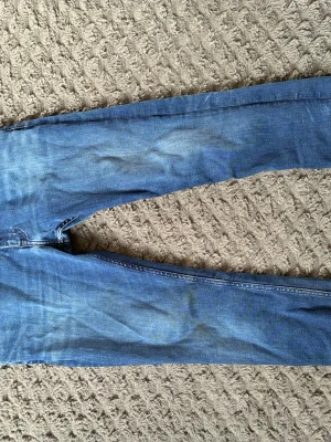 Blå slim fit jeans från Calvin Klein - Snygga blå slim fit jeans från Calvin Klein med klassisk femficksdesign och normal midja. Jeansen har en lätt tvättad look och subtila slitningar för en avslappnad stil. Perfekta för dig som gillar en smal passform och tidlös denim.