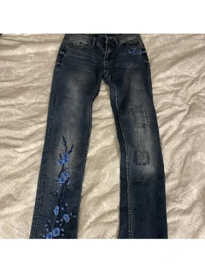 Mörkblå jeans med blå blommor - Snygga mörkblå jeans från G-STAR RAW med raka ben och unika blå blombroderier på vänster ben. Tillverkade i denim med cool tvätt och broderade detaljer.