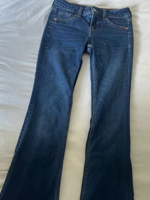 Mörkblå bootcut jeans - Säljer ett par mörkblå bootcut jeans. Jeansen har normal midja och utsvängda ben.