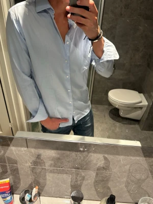 Ljusblå skjorta med knappar - Snygg ljusblå skjorta från John Henric. Riktigt schysst nu till sommaren. Skjortan är i bra skick och har inga skador. Skjortan är i storlek 40 vilket motsvarar M. Jag på bilden är 188cm. Hör av er vid frågor:)