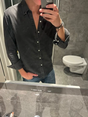 Svart skjorta med knappar - Säljer nu en snygg skjorta från John Henric. Riktigt snygg mörkgrå färg på skjortan som passar till mycket. Skjortan är i storlek 40 vilket passar dig som vanligtvis bär M. Jag är 188cm och den passar mig riktigt bra. Hör av er vid fler funderingar:)