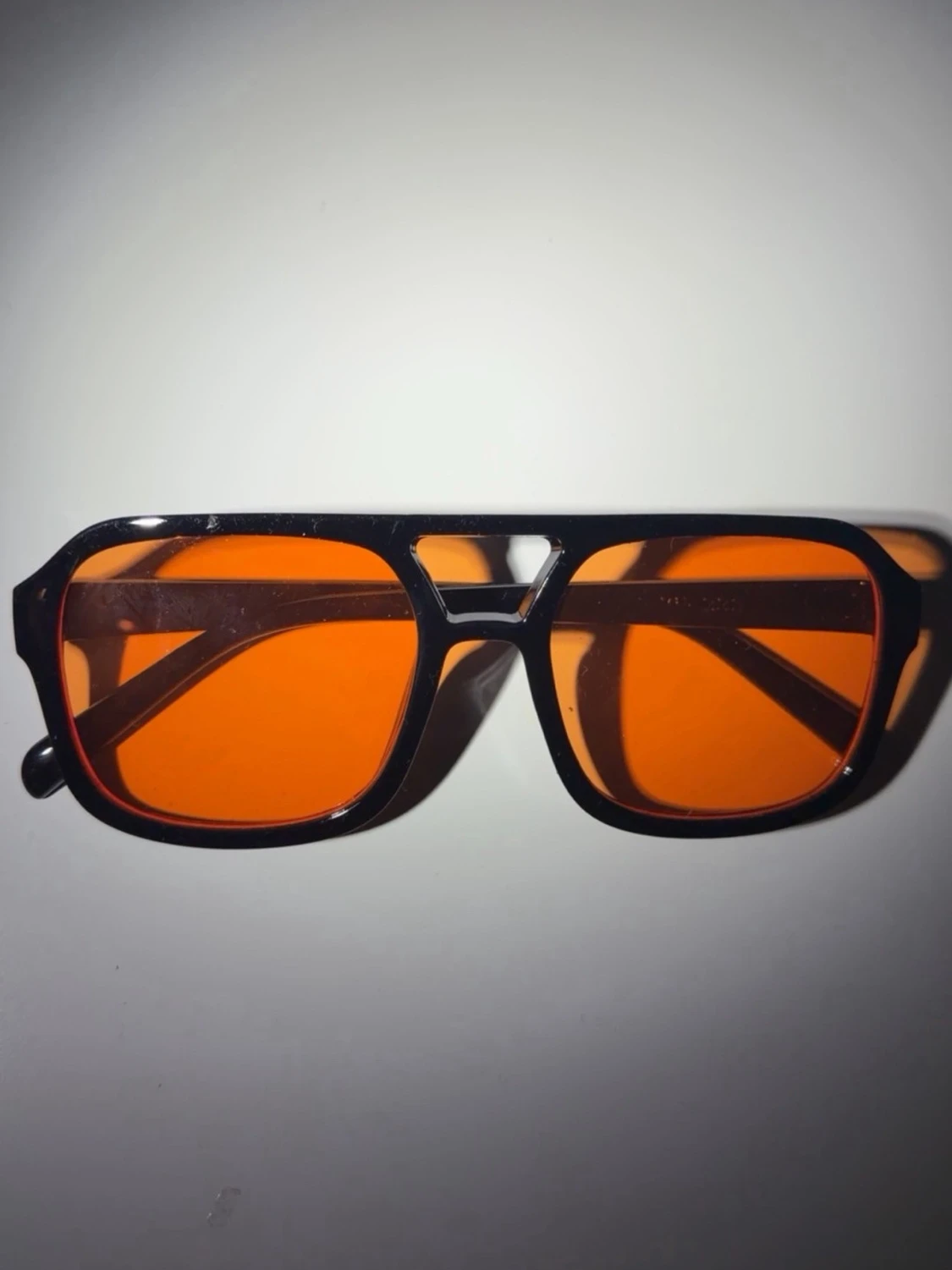 Svarta solglasögon med orange glas