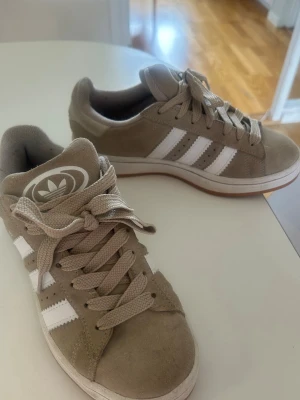 Adidas Campus – Beige/Taupe – Strl 37 1/3 - Säljer ett par Adidas Campus i en snygg beige/taupe färg med vita detaljer. Skorna är använda några gånger men är fortfarande i väldigt bra skick. Normala mindre tecken på användning finns, men de är väl omhändertagna och har mycket användning kvar.  ✨ Storlek: 37 1/3 ✨ Färg: Beige/Taupe ✨ Skick: Bra skick, använda få gånger ✨ Nypris: 1 499 kr  Perfekta vardagsskor som passar till det mesta.