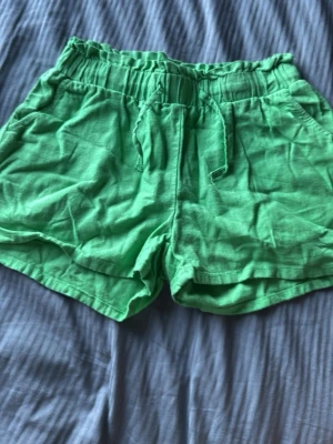 Gröna shorts  - Snygga gröna shorts med elastisk midja och snörning framtill. Tillverkade i mjuk bomull, perfekta för varma dagar. Shortsen har två sidofickor och en avslappnad passform.