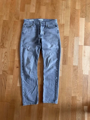 Jack and Jones jeans - Säljer ett par gråa jeans från Jack&Jones med rak passform och klassisk femficksdesign. Jeansen är i modellen loose/chris och storlek W29 L32. Perfekta för en avslappnad och trendig look.