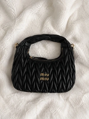 Svart Miu Miu väska - Jättesnygg svart väska från Miu Miu. Har tyvärr inte påse eller box kvar men har ett kvitto med köpbekräftelsen, den är köpt för 21 600 kr på deras egna hemsida. Använd bara några få gånger så i väldigt bra skick!🩷
