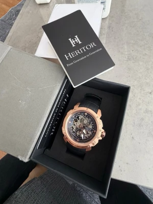Heritor automatisk klocka i roséguld - Snygg automatisk klocka från Heritor med genomskinlig urtavla och detaljer i roséguld. Svart läderarmband och mekaniskt urverk som syns både fram och bak. Perfekt för dig som gillar stilrena accessoarer med en lyxig touch.