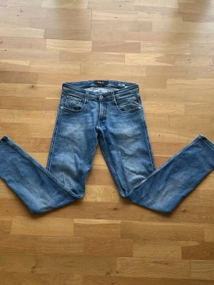 Blå slim fit jeans från Replay - Säljer ett par blå slim fit jeans från Replay, modell Anbass. Jeansen har klassisk femficksdesign, snygga slitningar och kontrastsömmar. Perfekta för dig som gillar en modern och avslappnad stil.