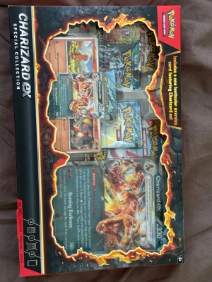 Pokémon Charizard EX Special Collection - Säljer en Pokémon Charizard EX Special Collection box med flera samlarkort och boosters. Boxen har svart och röd design med eld-detaljer och innehåller exklusiva Charizard-kort. Perfekt för Pokémon TCG-samlaren eller spelaren!
