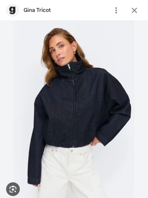 Mörkblå jeansjacka från Gina Tricot - Snygg mörkblå jeansjacka från Gina Tricot med hög krage och dragkedja framtill. Jackan har en boxy, oversized passform och långa ärmar. Perfekt för dig som vill ha en trendig och avslappnad look. Tillverkad i kraftigt jeansmaterial.