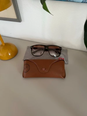 Ray-Ban Boyfriend - Säljer ett par klassiska Ray-Ban solglasögon med bruna bågar och tonade glas. Modellen har en fyrkantig form och kommer med ett snyggt brunt fodral. Perfekta för dig som vill ha en tidlös och stilren look.