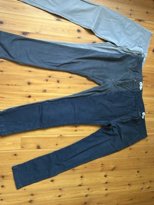 Mörkblå chinos med smal passform - Säljer 3 st chinos med smal passform och klassisk design. Byxorna har normal midja, bälteshällor och raka ben. Tillverkade i mjukt bomullstyg som ger en skön känsla och stilren look. Perfekta för dig som gillar en enkel men snygg stil. Alla är lika stora. 