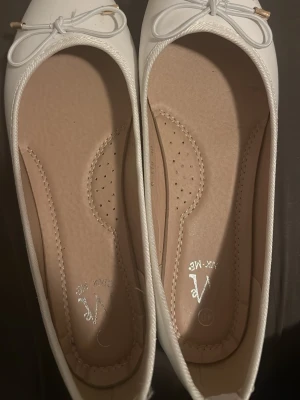 Vita ballerinaskor med rosett - Vita ballerinaskor. Bra till utspring. Omöjligt att få tag på några just nu. De är helt oanvända och är storlek 40 men är liten i storleken så de passar som 48/39