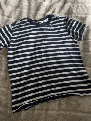 Randig svartvit t-shirt - Snygg t-shirt med svarta och vita  ränder. Klassisk passform och rund halsringning, perfekt för en avslappnad stil. Tillverkad i mjukt material som känns skönt mot huden.