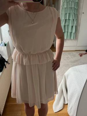 Ljusrosa  kort klänning från Vila - Supersöt ljusrosa kortklänning från Vila med volang i midjan. Passar perfekt nu till sommaren!! prislappen sitter kvar.