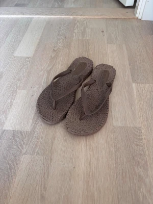 Bruna flip-flops från Ilse Jacobsen - Säljer ett par bruna flip-flops från Ilse jacobsen med flätad sula och tunna remmar i plast. Tofflorna har en enkel och stilren design som passar perfekt för sommaren. Färgen skiljer sig liten från bilderna. Dem är lite mer varma i verkligheten. Köpta på sellpy men i väldigt bra skick som man ser på bilderna. Hör av dig vid frågor🤗