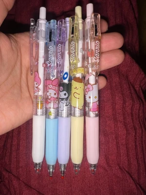 Sanrio gelpennor med figurer - Fem söta gelpennor från Sanrio med motiv av My Melody, Kuromi, Pompompurin och Hello Kitty. Pennorna har pastellfärgade grepp i vitt, blått, lila, gult och rosa samt transparent hölje med figurer. Perfekta för att skriva eller rita med extra stil. 1st får 30 kr. Set 120 kr
