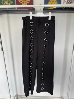 Svarta mjukisbyxor med metallringar - Unika svarta mjukisbyxor med bred passform och stora silverfärgade metallringar längs framsidan. Matchande hoodie finns på min profil om det är något som låter intressant!