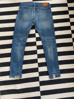 Blå skinny  jeans med slitningar från Abercrombie - Snygga blå skinny fit jeans med slitningar vid bensluten och lätt tvättade detaljer på låren och knäna. Klassisk femficksmodell med normal midja och dragkedjegylf. Perfekta för en avslappnad och trendig look. W30 L32