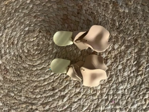 Beige statementörhängen i vågig form - Säljer ett par unika statementörhängen i beige med stora vågiga former och matta, guldiga plattor upptill. Örhängena har en modern och konstnärlig design som verkligen sticker ut. Perfekta för dig som vill ha något annorlunda och trendigt.
