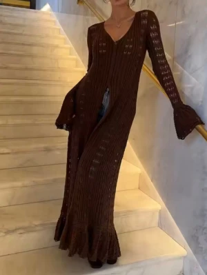 Brun lång stickad klänning cardigan  - Lång brun stickad klänning med v-ringning och knappar hela vägen framtill. Klänningen har långa ärmar med volang vid ärmslut och ett genombrutet mönster som ger en bohemisk känsla. Perfekt för dig som gillar unika detaljer och en avslappnad stil.