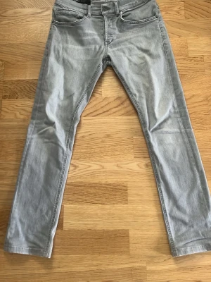 Dondup George jeans - Snygga ljusgrå jeans i slim fit-modell med klassisk femficksdesign och dragkedjegylf utan defekter. Jeansen har raka ben och subtila slitningar för en avslappnad look. Perfekta för dig som gillar en stilren och modern vibe. Pris kan diskuteras 😁