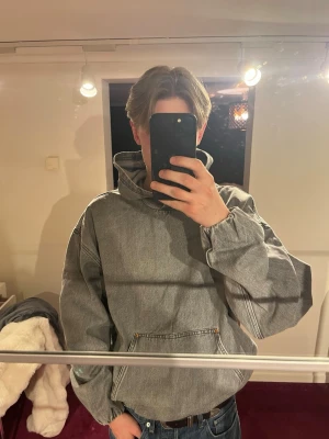 Grå oversized denim hoodie - Säljer en grå oversized hoodie i denim-look med stor huva och magficka. Hoodien har breda ärmar och resår i nederkanten som skapar en avslappnad känsla. Nästan oanvänt plagg. 