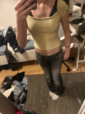 Gul ribbad croppad topp Gina Tricot - Säljer en ljusgul ribbad topp från Gina Tricot. Modellen är croppad med korta ärmar och har en söt volangkant vid halsringningen och ärmsluten. Perfekt för dig som gillar en enkel men trendig stil.