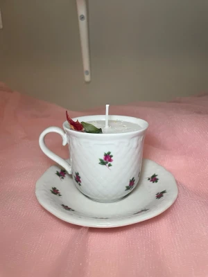 Doftljus i en tekopp med fat i blommig design  - Det här ljuset är gjort av återanvändbara material. Tekoppen är köpt secondhand och stearinet är från kyrkor som tänkte slänga det. Det här ljuset har en svag doft utav vanilj, så känsliga även kan använda det. Det här ljuset har även torkade blommor på som dekoration. 