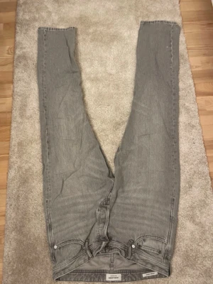 Grå jeans från Jack & Jones - Snygga grå jeans från Jack & Jones med klassisk femficksmodell och raka ben. Jeansen har en stilren look och är tillverkade i ett mjukt denimtyg som passar perfekt till en avslappnad stil.